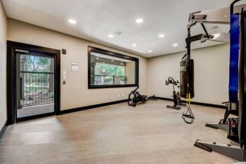 A gym with a variety of exercise equipment including a stationary bike, a rowing machine, and a weight machine.